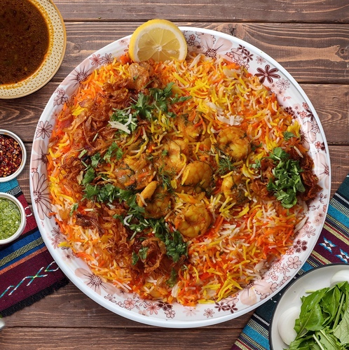 Shrimp Biryani - Basmati rice cooked in penne style with masala, freshly prepared with shrimp and a special mixture, served with adani ghee, cactus broth, tomato daqoos, two types of maabouj, onion box and watercress