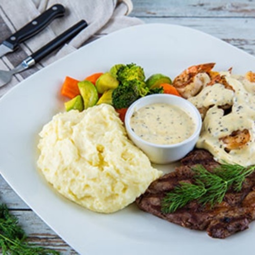 Steak And Shrimps - 340g rib eye , 8 pieces shrimp , mashed potato , mixed vegetables , served with Parmesan cheese sauce .