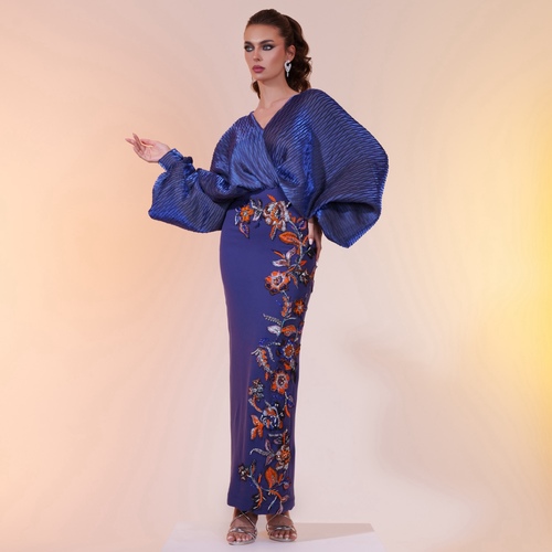 dark blue flower ornge - An elegant dress crafted from pleated fabric in deep blue, combined with Marina crepe for added sophistication. The gown is adorned with hand-embroidered floral patterns in vibrant colors, embellished with crystals and fine stones for a luxurious touch.