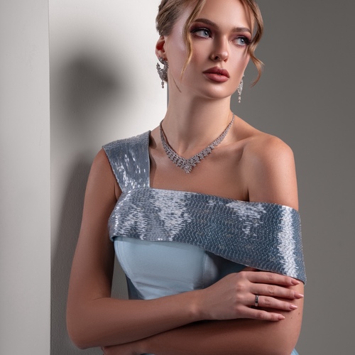 light blue mikado - A luxurious dress crafted from original Mikado fabric, characterized by its intricate multi-cut design. The shoulder is elegantly embellished with long, multi-colored beads that add a touch of sophistication and dynamic visual appeal.