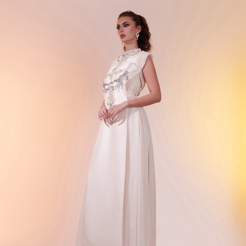 chiffon daraa cremy - A chiffon and Turkish taffeta dress adorned with pearls, crystals, and silver details. The inner layer is loose-fitting, while the outer layer can be adjusted in length, embellished with pearls and crystals of varying sizes for an elegant touch.