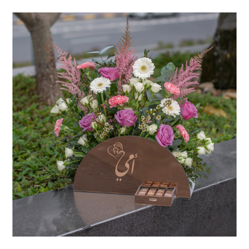 Mom 3 - Height: 60cm
Width: 50cm
A reflective acrylic box in bronze color that contains roses, baby roses, gerberas, cloves and mixed flowers with Belgian chocolates.