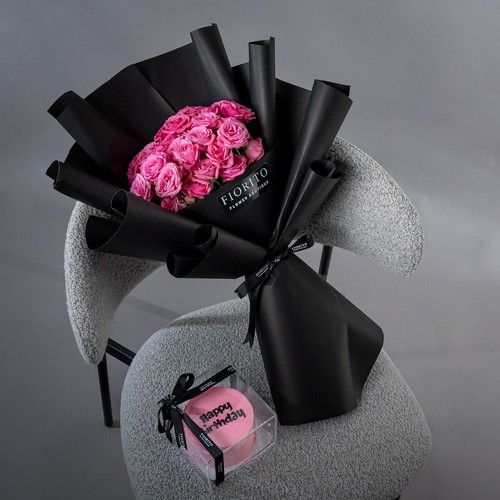 Earth Angel - Soft pink baby roses wrapped in a black wrapping paper with a cake symbolizing love and innocence.