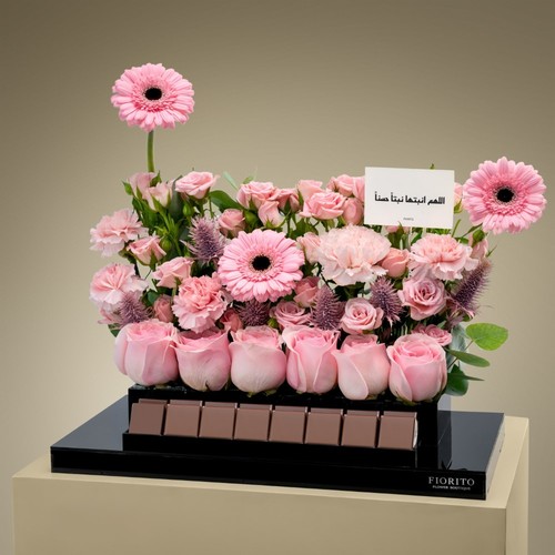 Joyful Welcome - An acrylic tray topped with baby roses, roses, gerbera, and eryngium with our delightful French chocolate. An elegant way to welcome them to their new world.