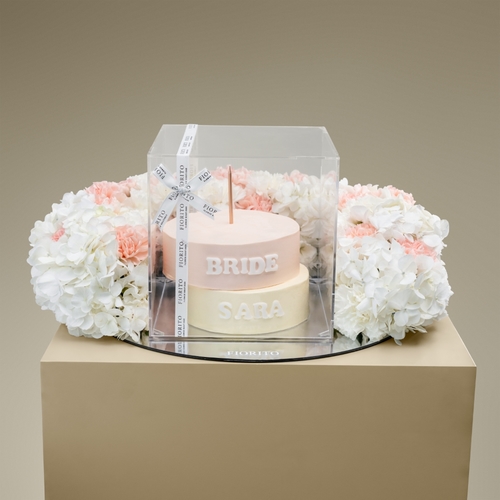 Precious Moment - A reflective glass tray topped with hydrangea and carnations with a delicate cake. This thoughtful gift is ideal for congratulating the bride on her most cherished occasion. Note: cake writing is customizable.