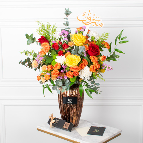 Classic And More - Roses, baby roses, chrysanthemums, and carnations arranged beautifully in a vase with a card, an acrylic topper, and chocolates.