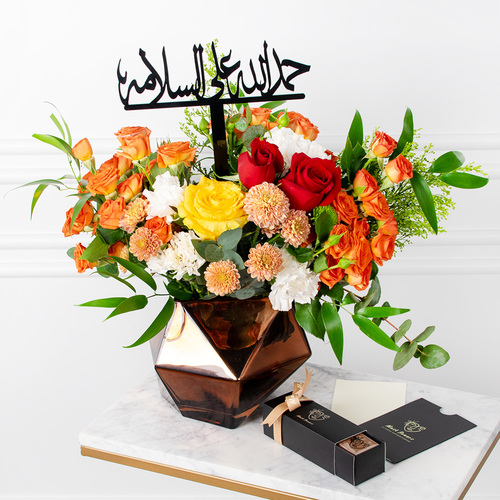 Browny Bouquet - Roses, baby roses, chrysanthemums, and carnations arranged beautifully in a vase with a box of chocolates, a card, and a topper.