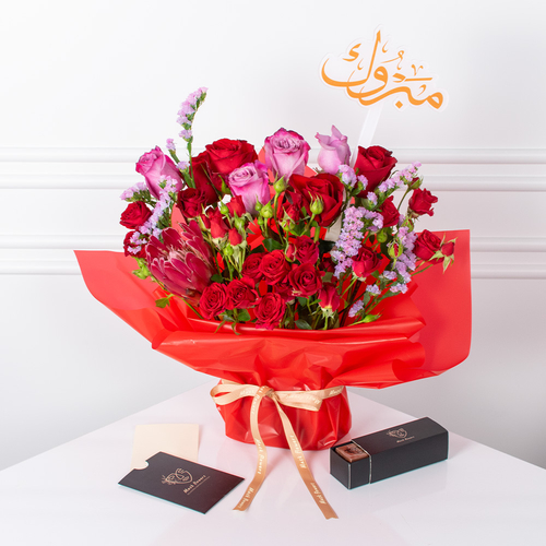 Petal Magic - A hand bouquet of roses, baby roses, and protea arranged beautifully with a card, chocolates, and an acrylic topper.