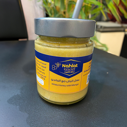 Nahlat Kuwait  - Kyrgyz White Honey With Mango 500g - When natural mango is added to Royal Kyrgyz White Honey, the benefits of the distinctive nutritional components of both ingredients are doubled. Here are some of the benefits they have in common: 
 1. *Immunity Booster:* Mango contains vitamin C, which boosts the body's immunity, and works alongside the antioxidants in honey to strengthen the immune system. 2. *Improves Digestion:* The natural fibers found in mango, in addition to the digestive properties of honey, contribute to improving gut health and treating digestive problems. 3. *Source of Energy:* The mixture provides quick energy thanks to the natural sugars found in honey and healthy carbohydrates in mango. 4. *Supports Skin Health:* Mango contains vitamins and minerals that nourish the skin, and both ingredients can help moisturize, purify, and improve the appearance of the skin. 5. *Improves Vision:* Mango is rich in vitamin A and carotenoids that support vision health, making this mixture beneficial for the eyes. 6. *Anti-Inflammatory:* Both ingredients have anti-inflammatory properties, which helps relieve inflammation and pain. 7. *Support Heart Health:* The vitamins and minerals found in mango, in addition to the benefits of honey in improving cholesterol levels, help support heart health. 8. *Promote General Health:* Mango contains a wide range of vitamins and minerals such as vitamin E, potassium and magnesium, which support general health and fight diseases. 9. *Promote Brain Health:* Mango contains B vitamins, which support brain function and improve memory and concentration. 
 Eating this combination can provide great nutritional support for the body thanks to the benefits of royal Kyrgyz white honey and natural mango.