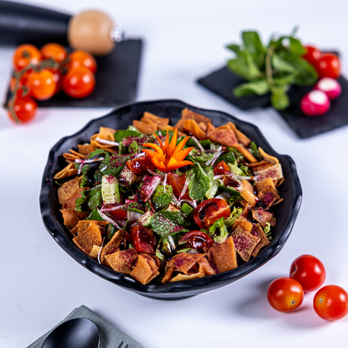 Fattosh - A selection of fresh mixed vegetables and tomatoes seasoned with a tangy sumac dressing topped with crispy Arabic bread