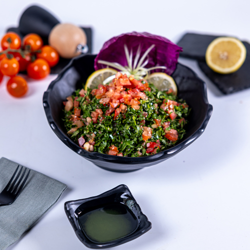 Taboula - Our traditional salad made with fine cut parsley tossed with diced tomatoes and fine cut white onions, mixed with borghoul and drizzled with lemon and olive oil dressing.