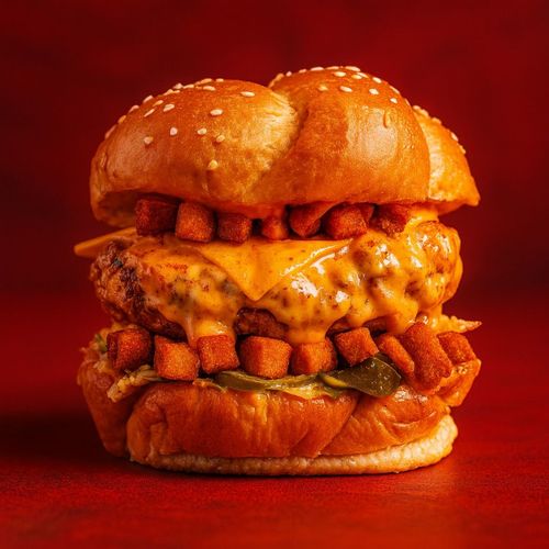 Zangoori - Ignite your taste buds with our Zangoori sandwich, A crispy sesame bun encases a juicy chicken breast smothered in our fiery dynamite sauce, layered with fresh lettuce, melted cheese, and topped with a fiery kick of peri peri hot fries.