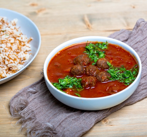 Dawood Basha - Meatballs cooked in tomato sauce topped with fried potato cubes and served with vermicelli rice.