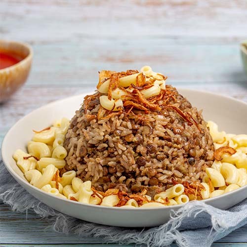 Koshari Umm Tariq - Koshari cooked in Umm Tariq’s special way, topped with macaroni and fried onions served with a special tomato sauce.