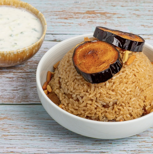 Eggplant Maqluba Chicken - Rice cooked with eggplants and chicken breast cubes garnished in nuts served with cucumber yogurt salad.