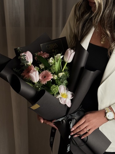 touch of pink boquet - باقة أزهار أنيقة تجمع بين اللون الوردي الرقيق والزهور البيضاء مع لمسة من الأوراق الخضراء، مغلفة بورق أسود فاخر مع شريط أنيق، مثالية لإهداء لحظات خاصة ومميزة.