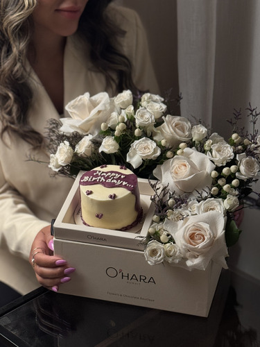 O’Hara Delight - تنسيق عيد ميلاد فاخر
صندوق أنيق يجمع بين فخامة الزهور البيضاء ونعومة التفاصيل، مزود بكيكة صغيرة بتصميم بسيط مكتوب عليها عبارة 