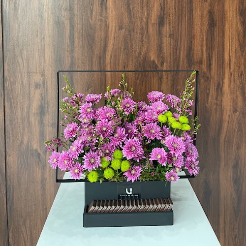 Arizona - A black wooden basket with metal handle contains pink chrysanthemum, green chrysanthemum and wax flower with Belgian chocolates.  Height: 52cm – Width: 53cm