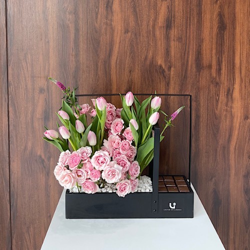 Lavish - This black wooden basket contains pink tulips, pink baby roses and veronica gaya with Belgian chocolates.  Height: 49cm – Width: 52cm