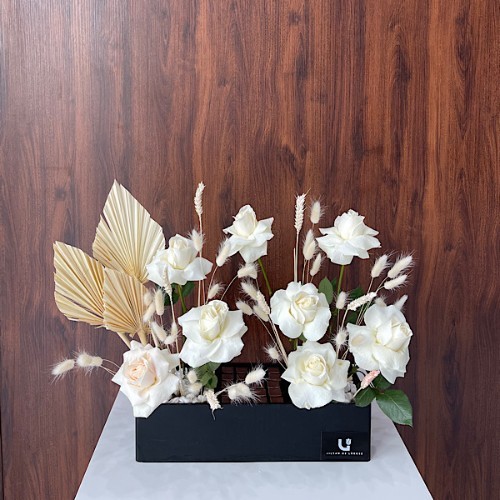 Limelight - This black wooden rectangle contains white roses, white tritium, and anahaw leaves with Belgian chocolates.  Height: 48cm – Width: 63cm