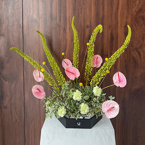 Either Way - This black wooden hexagon contains eremurus, anthurium, craspedia and carnation flowers. Height: 93cm – Width: 97cm