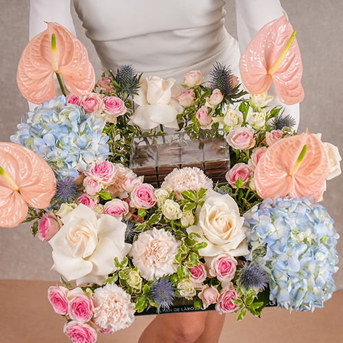 Aiyana - An acrylic tray that contains white roses, anthuriums, pittosporum, hydrangea and mix of baby roses with Belgian chocolates. Height: 38 cm - Width: 53 cm