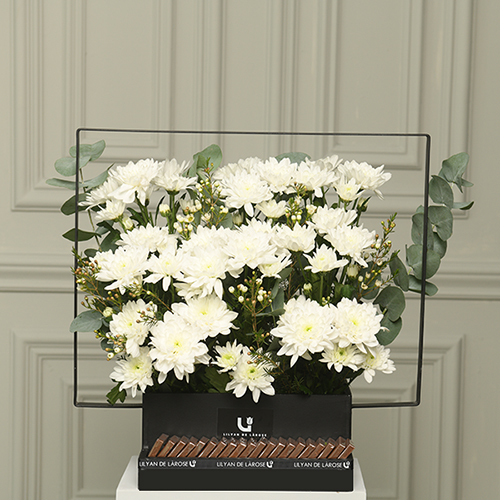 White Arizona - A black wooden basket with contains white chrysanthemum, eucalyptus and wax flower with Belgian chocolates.