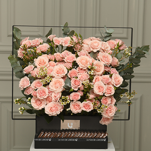 Light Sybya - A black wooden basket with contains baby roses, white wax, and eucalyptus with Belgian chocolates.