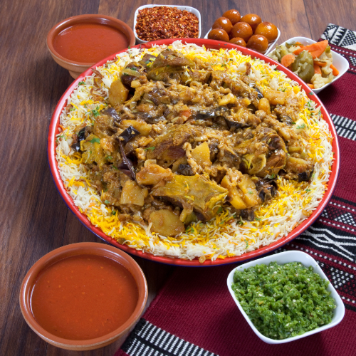 Maklouba Chicken Tray - Basmati rice with chicken and vegetables prepared with spices served with broth, red mabog, green mabog and Luqaimat