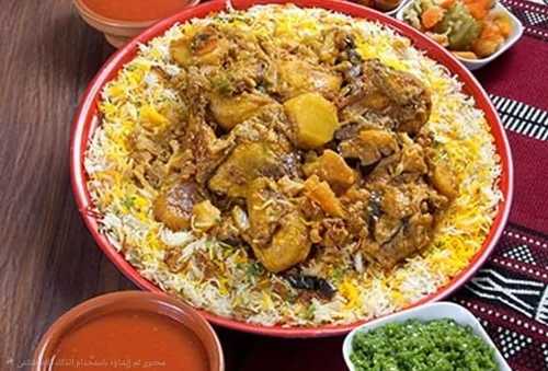 Maklouba Chicken Tray - Basmati rice with chicken and vegetables prepared with spices served with broth, red mabog, green mabog and Luqaimat
