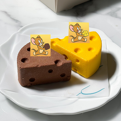 Tom & Jerry Mango Strawberry Cheesecake   -   Chocolate Caramel Cheesecake - A playful fruity indulgence layered with creamy mango cheesecake filled with a velvety mango center, resting on a soft vanilla sponge base. Hidden inside, a bright strawberry layer adds a juicy burst of flavor. The whole creation is coated in a crisp white chocolate shell, giving a fun contrast of crackling crunch outside and smooth cheesecake inside. A dessert full of creamy, soft, and crunchy textures – just like Tom & Jerry, always chasing and surprising!  
 A playful mix of indulgence – smooth chocolate cheesecake with a rich caramel swirl, layered over a crunchy biscuit base and filled with soft, moist chocolate richness. The finale comes with a crackling white chocolate crunch coat, giving every bite a perfect balance of creamy, gooey, and crunchy textures. A cheesecake that’s as mischievous and irresistible as Tom & Jerry!