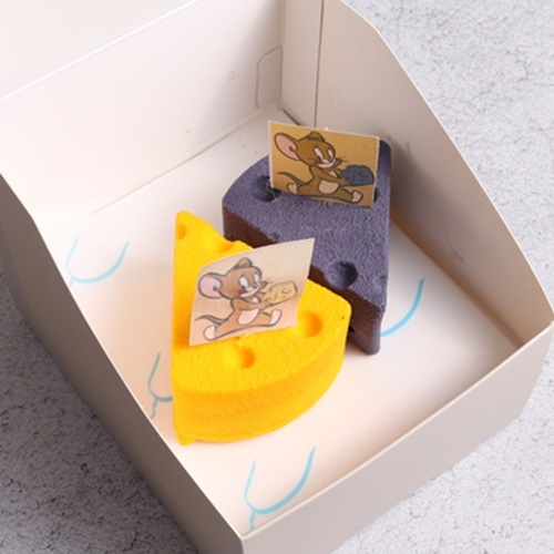 Tom & Jerry Berry Cheesecake   -  Mango Strawberry Cheesecake - A cheeky berry chase of flavors – rich berry cheesecake filling swirled with a juicy berry compote for a sweet–tangy surprise. At the base, a buttery biscuit layer adds a crunchy bite, while the whole creation is wrapped in a crisp white chocolate shell with extra crunch. A fun mix of creamy, juicy, and crunchy textures that’s as playful as Tom & Jerry’s adventures! 
 A playful fruity indulgence layered with creamy mango cheesecake filled with a velvety mango center, resting on a soft vanilla sponge base. Hidden inside, a bright strawberry layer adds a juicy burst of flavor. The whole creation is coated in a crisp white chocolate shell, giving a fun contrast of crackling crunch outside and smooth cheesecake inside. A dessert full of creamy, soft, and crunchy textures – just like Tom & Jerry, always chasing and surprising!