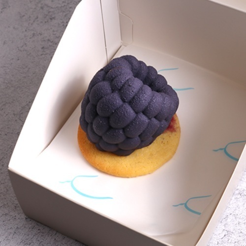 Berry Noir - A cake shaped like a berry, with layers of red velvet and berry cream, filled with blueberry, coated in white chocolate with a delightful crunch.