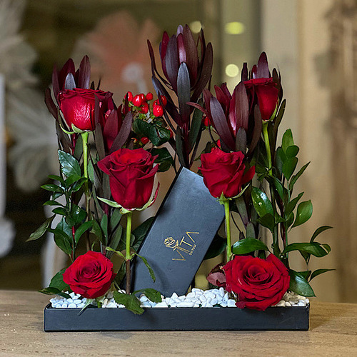 Vita Dei Fiori - Amera - Black tray contains red roses, safari sunset and green leaves with a box of chocolates. H : 55 W :  30