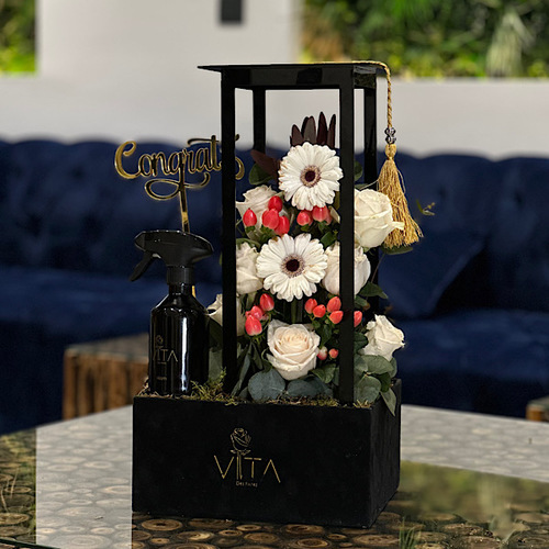 Cvek - Black box contains white gerbera, safari sunset, green leaves ,orange baby roses, graduation cap , congrats gold stick with spray perfume. Height: 55 Width: 25