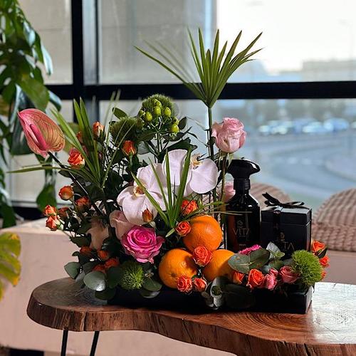 Lora - A black tray that contains orchid, green leaves, dyantos, pink anthurium, orange pink baby roses, fucia baby roses with a box of chocolate & spray perfume. Height: 25 Width: 35