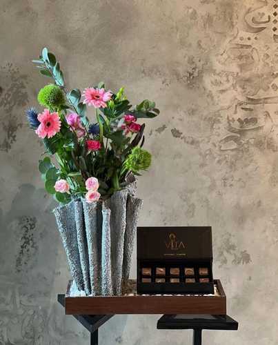 ikra - A wooden tray that contains pink gerbera pink baby roses fuchsia baby roses and dianthus Hypericum green Eryngium green leaves and a box of chocolates. Height: 50 Width: 30