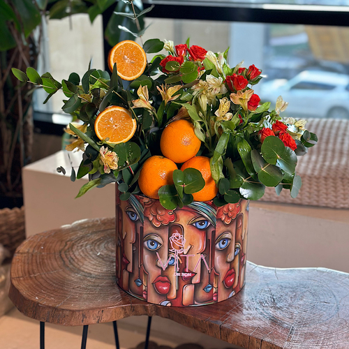 Origami - The round box contains fresh oranges, green leaves, orange baby roses, and yellow alstroemeria. Height: 50 Width: 25