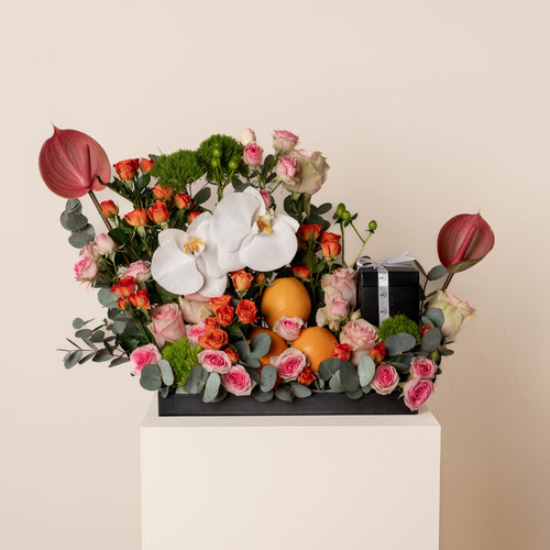 Tred - A black tray that contains orchid, green leaves, dyantos, pink anthurium, orange pink baby roses, fucia baby roses with a box of chocolates. Height: 35 Width: 25