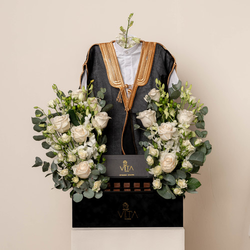 Bisht - A black box contains white roses, white baby roses and greens with baby deshdasha, baby bisht and a box of chocolates. H : 50 W : 35