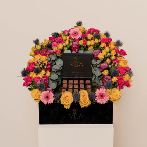 Eleganza - A black box contains roses and baby roses, hypericum, gerbera, eryngium and eucalyptus with a box of chocolate. Height: 50 Width: 40