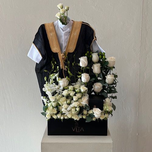 rock - A black box contains white roses, white baby roses white baby orchid and Hypericum green with baby dishdasha, baby bisht and a box of chocolates. Height: 50 Width: 30