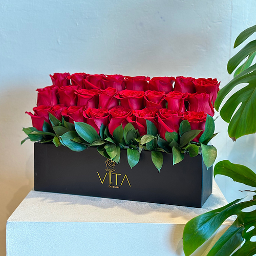 Aurora - A black box containing red roses with green leaves arranged beautifully. Height: 25  Width: 30