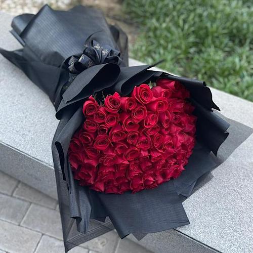 Vee 200 - A hand bouquet of 100 roses in black wrapping. Height: 80  Width: 50