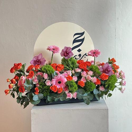 Veria - A tray elegantly filled with pink and orange baby roses, purple cymbidium, gerbera and green leaves and acrylic hajj topper. Height: 40 Width: 25