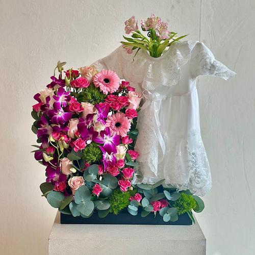 Jerry - A tray that contains roses, baby roses, gerberas, and baby orchids with eucalyptus leaves. Comes with a white dress for a newborn baby. Height: 60 Width: 20