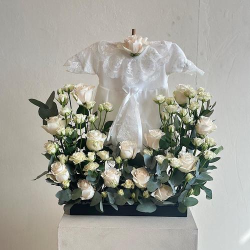 Palau - A tray that contains white roses and baby roses with eucalyptus leaves. Comes with a dress for a newborn baby. Height: 60 Width: 20