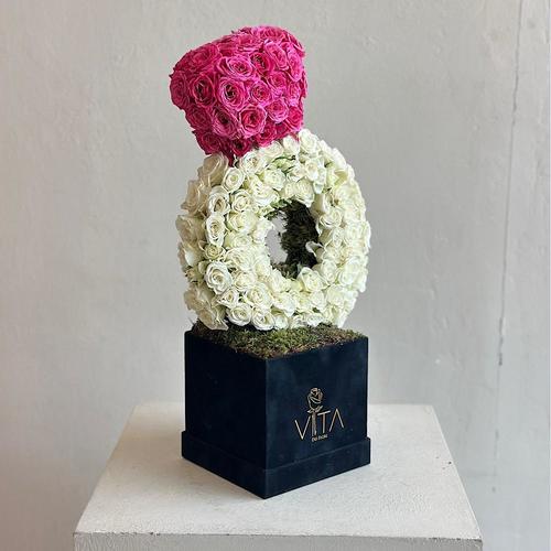 Ringoino - A black box contains ring shape with white baby roses and fuchsia 
 Height: 55 Width: 18