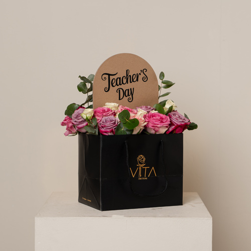 The Tec - A black bag that contains pink, purple roses, green leaves with stand teachers day.