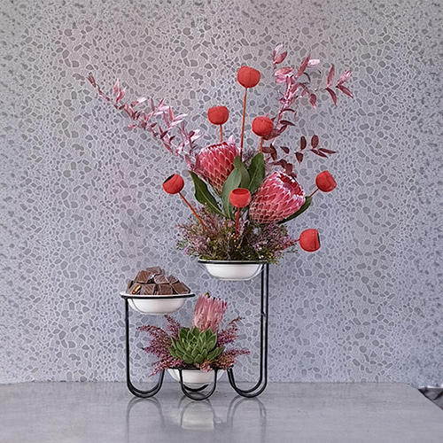 Vivre XX - Height: 100 cm
Width: 60 cm

A stand contains bell cups flowers, ruscus, protea, echeveria and chocolates